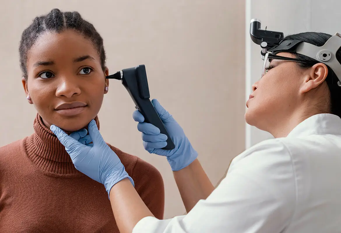 Otorrinolaringóloga analizando el oído de una paciente con un otoscopio